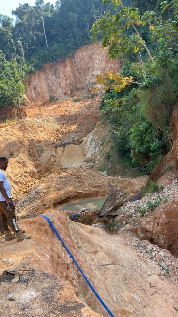 A man on a dirt road beside a river, located near the new Liberia mining company site focused on gold mining