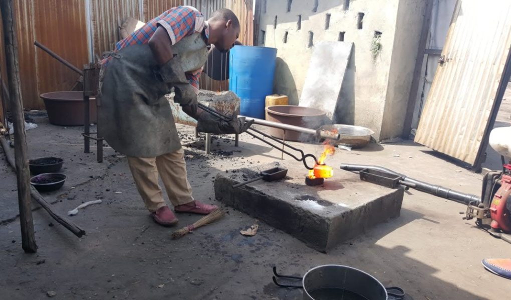 In a workshop, a man is engaged in the processing of gold, working diligently on the metal object for the Liberia mining company