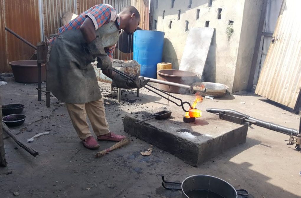 In a workshop, a man is engaged in the processing of gold, working diligently on the metal object for the Liberia mining company