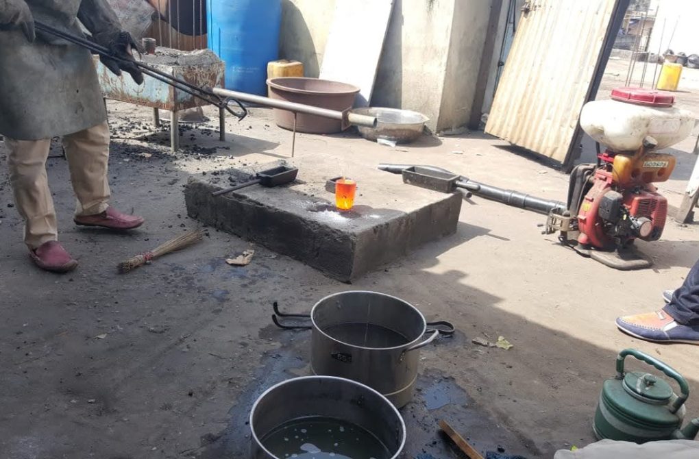 In a workshop, a man is engaged in the processing of gold, working diligently on the metal object for the Liberia mining company