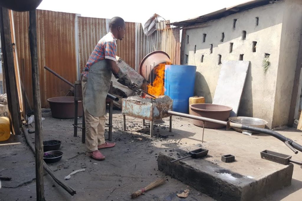 A man diligently works on a metal object in the yard of the New Liberian Mining Company, highlighting mining activities