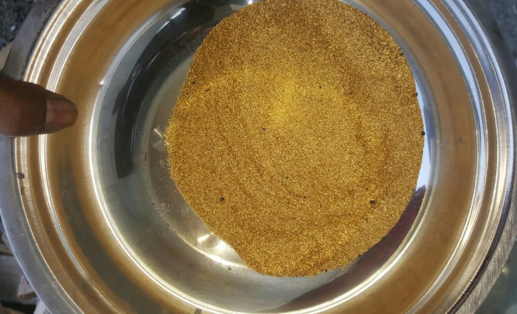 A person holds a bowl half full of gold, during processing at the new Liberia mining company