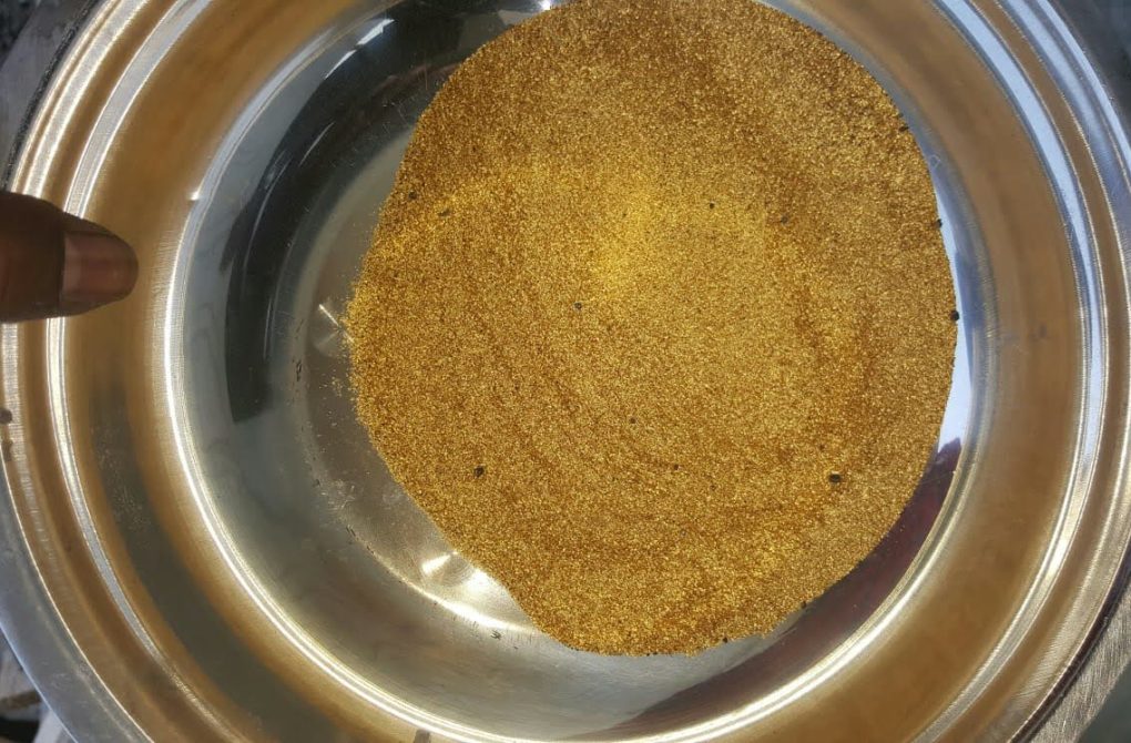 A person holds a bowl half full of gold, during processing at the new Liberia mining company